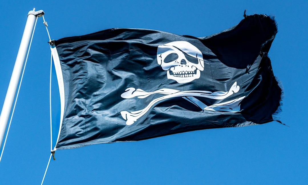 A black pirate flag with a skull emblem waves against the sky.